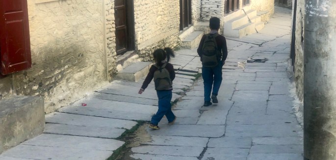 A boy leads his younger sister to school via a leash