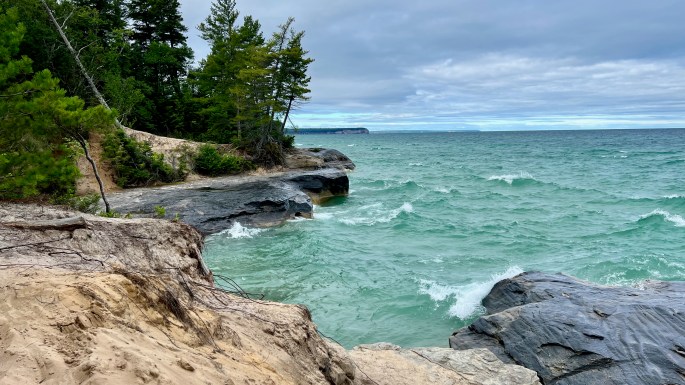 Whitecapped waves splash on the shorline at the cloudy start of the day